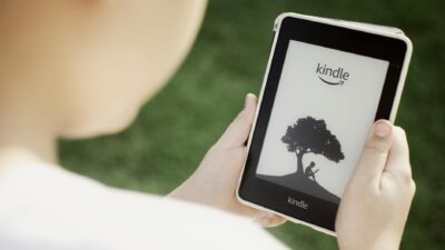 A child holds a Kindle device outdoors, highlighting the ease of reading with technology.