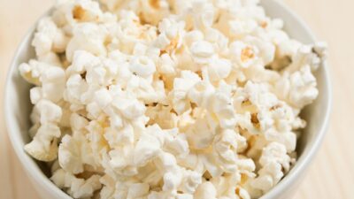 Close-up of freshly popped popcorn in a white bowl, perfect for a movie night snack.
