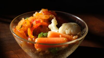 cooked rice with sliced carrots and green vegetable in clear glass bowl