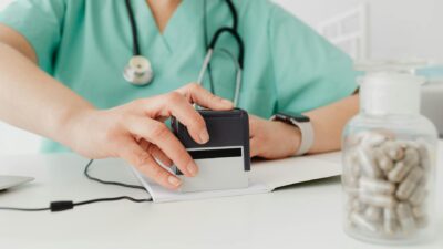 Close-up of a doctor stamping a prescription with a bottle of pills on a desk.