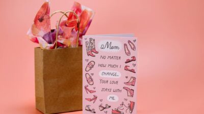 Mother's Day card with heartfelt message and gift bag on pink surface.