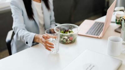 Business professional in office setting preparing to enjoy a healthy lunch while working on a laptop.