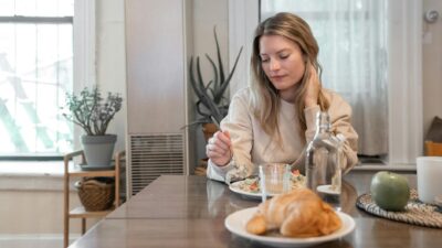 A woman indulging in a healthy salad at a cozy indoor setting, promoting wellness.
