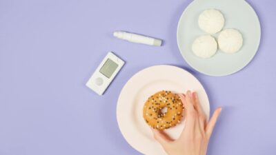 Flat lay of diabetes-related items with food on a pastel background.