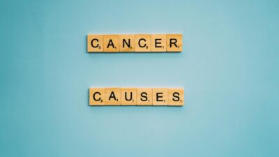 Scrabble tiles spelling 'Cancer Causes' on a light blue background, highlighting awareness.