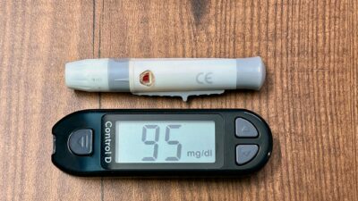 Close-up of a glucometer reading 95 mg/dl with a lancing device, ideal for diabetes and healthcare imagery.