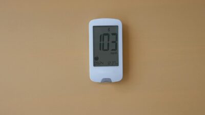 A digital glucose meter displaying blood sugar level on a beige background, ideal for healthcare themes.