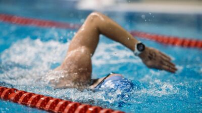 A focused swimmer performs a freestyle stroke in a competition-grade indoor pool.