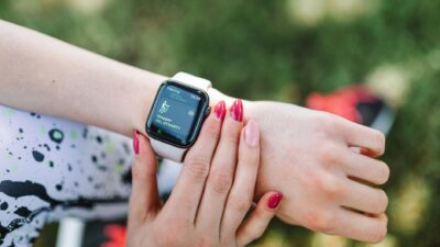 Close-up of a woman using a fitness tracking smartwatch during exercise outdoors.
