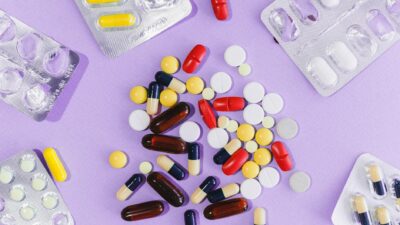 A variety of colorful pills and capsules displayed on a purple background in blister packs.