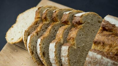 Close-up of freshly sliced healthy wheat bread on a wooden board, showcasing texture.