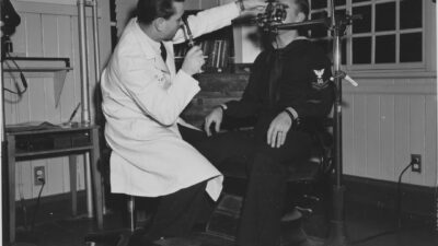 Doctor examines patient's eye with equipment.