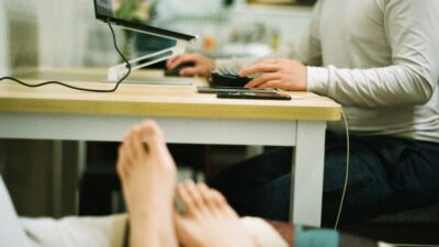 a person sitting at a table with a laptop and a cell phone