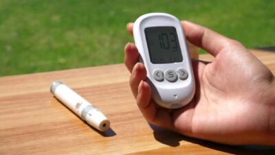 a person holding a digital thermometer next to a pen