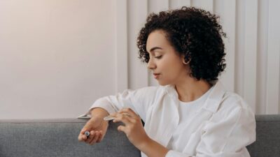 A young woman applies essential oil while relaxing indoors, promoting wellness and self-care in a calming environment.