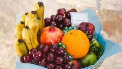 Vibrant arrangement of mixed fruits including bananas, grapes, and oranges in a decorative setting.