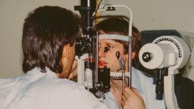 Optometrist examining a patient's eye with equipment.