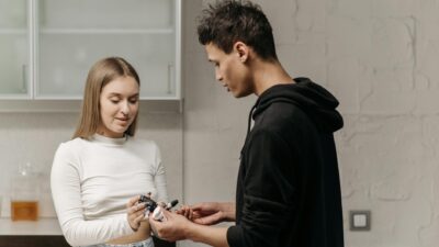 A young couple checking blood sugar levels using a glucometer indoors for diabetes management.