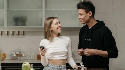 Smiling couple checking blood sugar with glucometer in kitchen.
