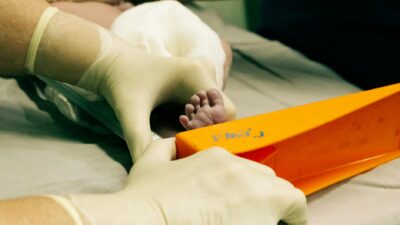 Newborn's foot being measured by a nurse in medical setting with care.