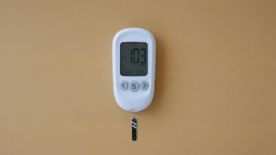 Close-up of a digital glucose meter displaying blood sugar level on a brown surface.