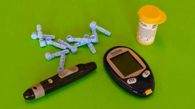 Essential diabetes equipment including glucometer and lancets on a green backdrop.