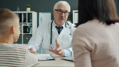 Doctor consults with mother and child in office.
