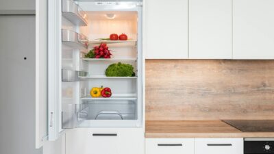 Contemporary kitchen with refrigerator filled with fresh bright tomatoes lettuce and bell peppers