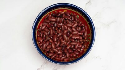 Top view of raw kidney beans in a colorful bowl on a marble surface, highlighting natural nutrition.