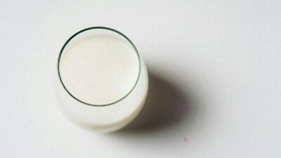Minimalist image of a glass of milk on a white background, shot from above.