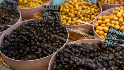 Close-up of bowls filled with different types of olives in a vibrant marketplace.