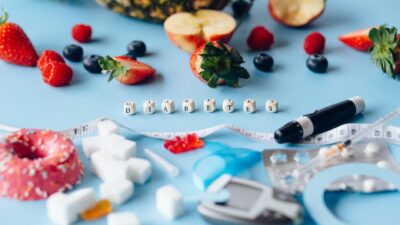 Conceptual image highlighting diabetes with healthy fruits and medical tools on a blue background.