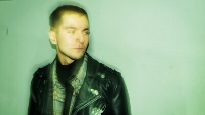 Portrait of a man wearing a leather jacket facing sideways with a defocused effect, indoors.