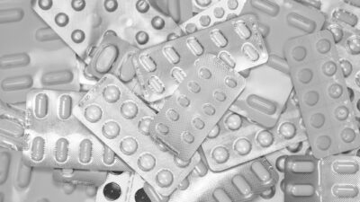 Monochrome close-up of assorted blister packs with pills, highlighting pharmaceutical packaging.