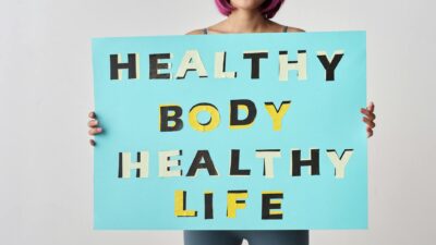 A woman holds a motivational poster advocating a healthy body and life for wellness.