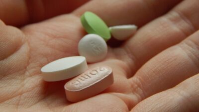Hand holding various colorful pills and capsules.