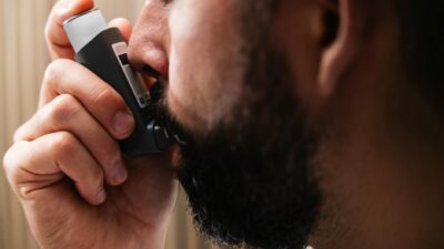 A close-up image of a man using an inhaler, highlighting respiratory health concepts.