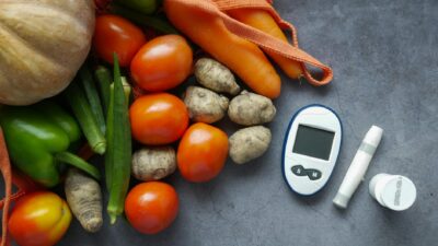 A flat lay of diabetes equipment alongside fresh vegetables promoting healthy lifestyle.