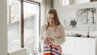 Young woman managing diabetes indoors with an insulin pen in a bright living room.