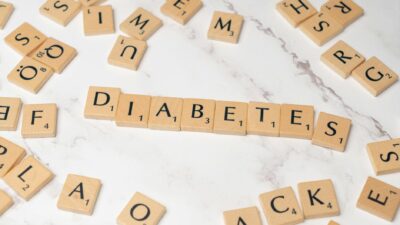 Scrabble tiles spelling 'DIABETES' on a white marble background. Emphasizes awareness and education.