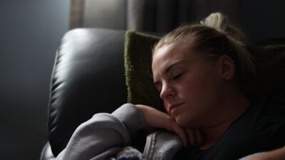 boy in gray hoodie lying on black leather couch