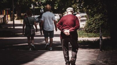 man in red hoodie walking on sidewalk during daytime