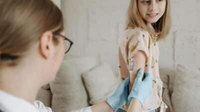A young girl receives an insulin checkup from a medical professional at home, managing diabetes.