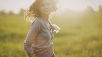 a woman standing in a field with her hair blowing in the wind