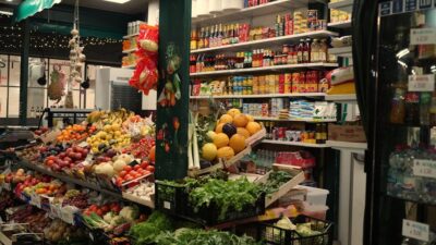 A grocery store aisle stocked with fresh produce and shelves.