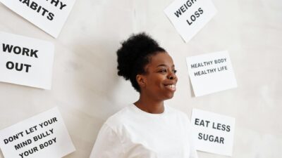 Portrait of a smiling woman surrounded by health motivation signs on a white background, promoting a healthy lifestyle.
