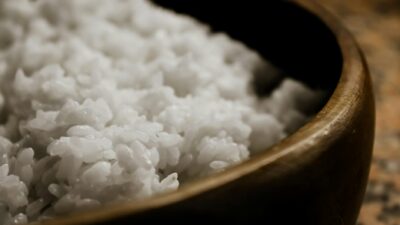 A detailed close-up view of freshly steamed white rice served in a wooden bowl.