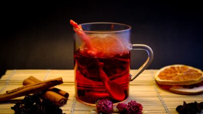Glass mug with red beverage, cinnamon sticks, and dried fruit.