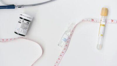 Collection of medical supplies including ampoules, vials, and measuring tape on white surface.