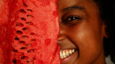 A cheerful person holding a watermelon slice close to the face, showcasing a joyful expression.